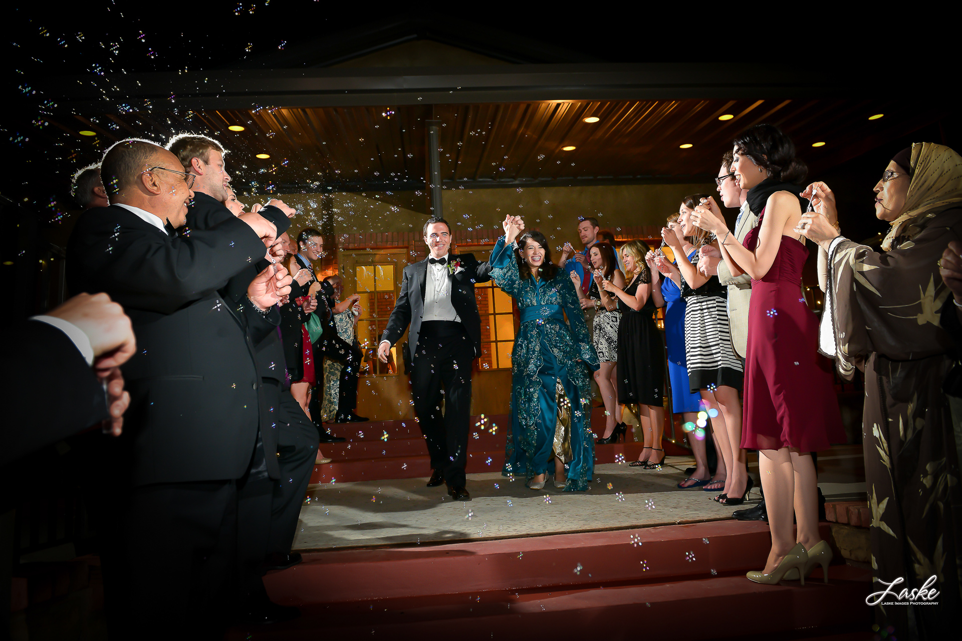 Bride and Groom Leaving the Wedding Reception surrounded by guests blowing bubbles on their wedding day.